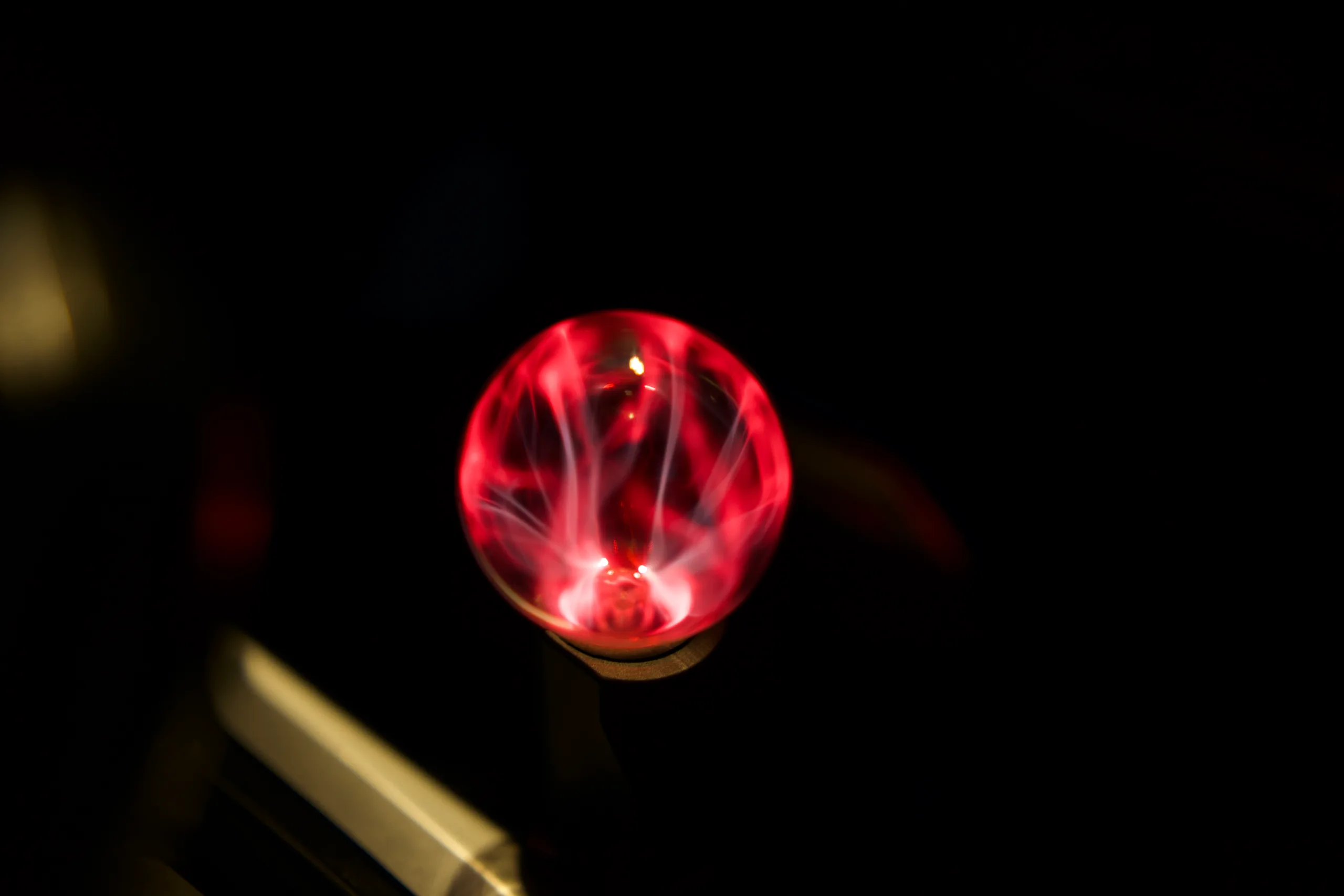 The plasma globe lit in a dark car interior, filaments branching inside the glass, chrome console trim catching its glow